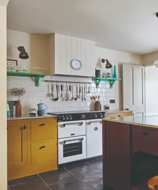 regole per rinnovare la cucina, cucina rosa e verde con isola e pensile rosa, alzatina in tonalità verdi, barra appendiabiti in ottone, pavimento in piastrelle grigio scuro