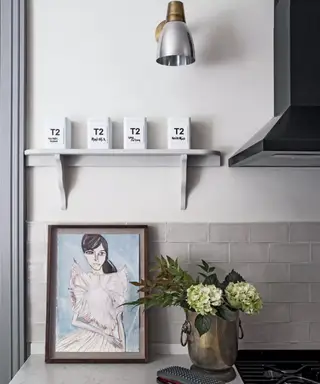 Gull vegglamper over en blå kjøkkenenhet med marmor benkeplater.