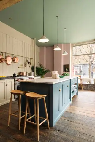 Tre pendellys over en blå øy i grønn og rosa kjøkkendesign.