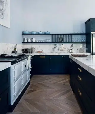 Área de cocina con aga azul claro, encimeras y gabinetes empotrados de mármol blanco, pisos de madera oscura
