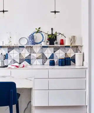 Hvitt kjøkken med fargerike blå og hvite bakplater, elegante skap og åpne hyller.
