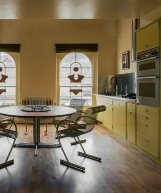 Cocina amarilla con techo brillante y vidrieras con accesorios cromados.