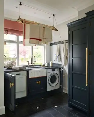Ein traditioneller Wäscheständer aus Holz, der von der Decke in einem weißen Waschraum mit schwarz gestrichenen Schränken montiert ist.