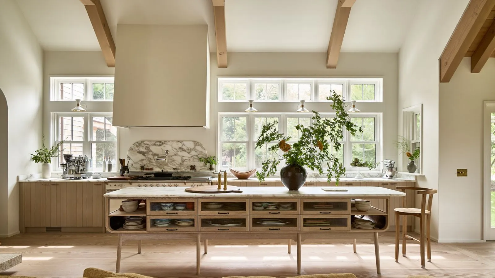 Et kystskandinavisk køkken med varmhvide træmøbler og højt til loftet' loading='lazy' title=