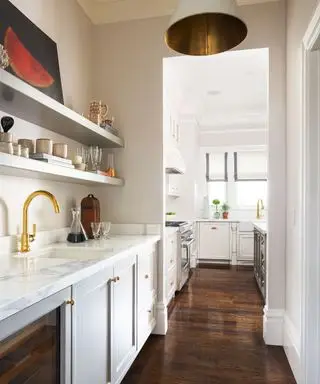 Cocina y lavadero modernos, suelos de madera oscura, armarios blancos y encimera de mármol.