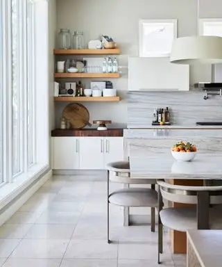 Cocina moderna con isla, estanterías de madera, mesa de comedor con asientos