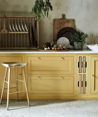 Idee per mobili da cucina dipinti in giallo senape con pavimenti in pietra, pareti strutturate e accenti in legno.
