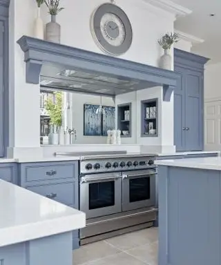Mobili da cucina dipinti di blu contro pareti bianche con alzatina a specchio.