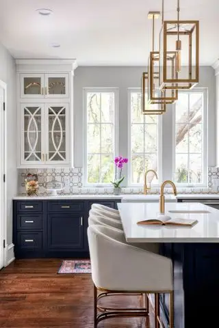 Idee per mobili da cucina dipinti con mobili dipinti di blu notte, ripiani bianchi, pavimenti in legno scuro e un'isola cucina con posti a sedere imbottiti.