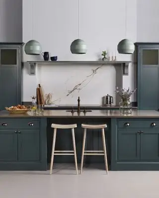 Idee per un mobile da cucina verniciato grigio-verde scuro con tre lampade a sospensione verde chiaro e pareti e pavimenti chiari.
