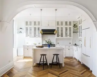 cucina bianca con isola e pavimento in legno
