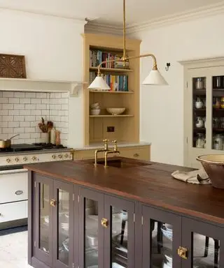 Cocina amarilla Devol con isla marrón oscuro con accesorios, herrajes y grifería de latón
