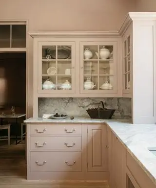 Cocina inglesa rosa con gabinetes superiores con frente de vidrio