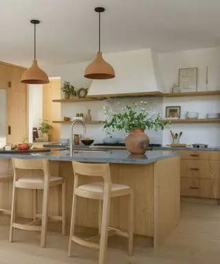 Cocina con gabinetes de madera y gran campana extractora blanca enlucida