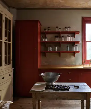 Pequeña cocina blanca estilo shaker con encimeras de madera de iroko oscura y suelo de terracota.