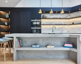 Cozinha com armários azuis, ilha de concreto e iluminação led