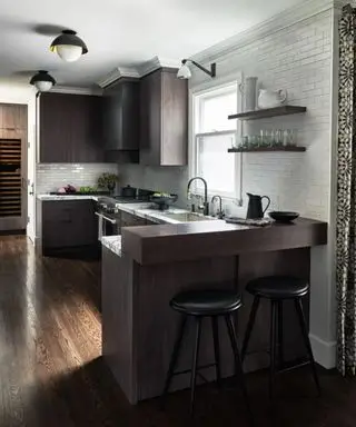 Cocina de madera oscura con paredes blancas y distribución peninsular.