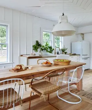 Cocina moderna de estilo rústico con armarios blancos y una mesa de estilo rústico de madera.