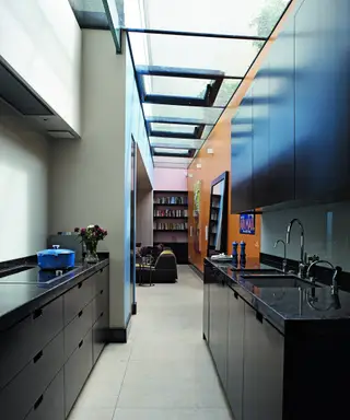 Ein Beispiel für Küchenstile, das eine Küche mit einer Holzinsel, Holzböden und schwarzen Schränken zeigt