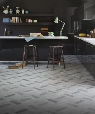 Ein dunkles Küchenkonzept mit einem Beispiel für Ideen für mehrfarbige Vinyl-Küchenböden in Holzoptik, verlegt im Fischgrätenmuster.