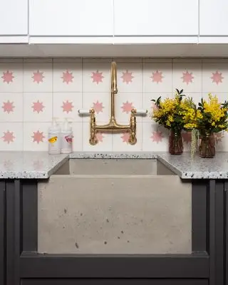 betonové umyvadlo s mosaznými kohoutky a růžovými a bílými enkaustickými dlaždicemi