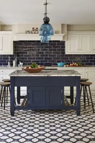 Et blåt og hvidt køkken med geometriske gulvfliser og et kvadratisk køkkenø-design og morgenmadsbar.