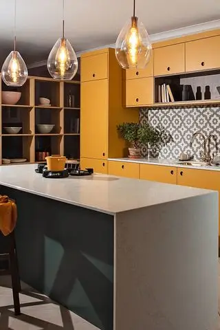 Design af en køkkenø vist i et farverigt køkken med gule skabe, en blågrøn morgenbar og geometrisk flisebelagt bagplade.