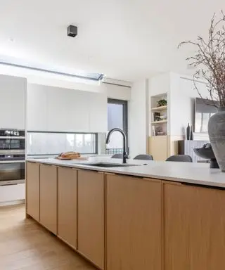 Una cocina con gabinetes de madera y encimeras mezcladas en blanco.