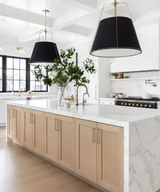 Una encimera de cuarzo en una cocina de madera blanca con lámparas y cristales negros.