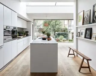 Un elegante ejemplo blanco de ideas de cocina de galera, con isla y puertas plegables.