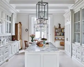 Cocinas de galera ilustradas por una gran sala neutra con isla de mármol y muebles de madera.