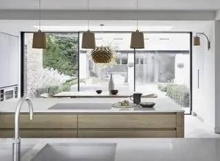 cucina bianca con mobili in legno, doppie isole cucina e pendenti in legno