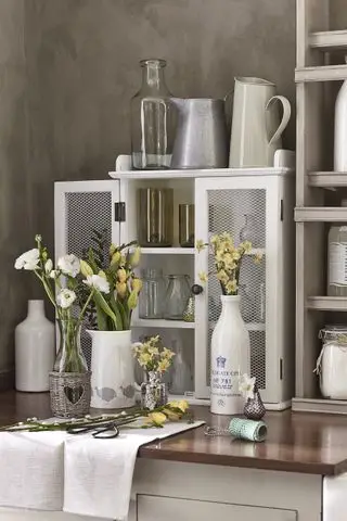 Vaser med nyskårne blomster på benkeplate.