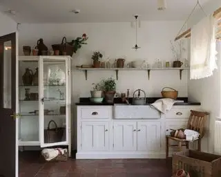 En eklektisk vaskeromside med åpne hyller fulle av vaser, potter og kurver fulle av friske blomster.