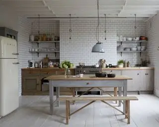 Moderne køkken med hvide fliser, hvidt trægulv, gråt træ køkkenskabe, træ spisebord i midten eller værelset, creme smeg køleskab på venstre side