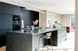 Et moderne køkken fra Lundhs med mørk granit køkkenø og grebsfrit skab.