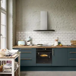 Moderne køkkenideer af Smeg, med havgrønt skab, messinggreb og malet murstensvæg.
