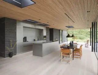 Moderne køkkenideer i et langt, slankt gråt plan med træpanelloft, sort bord og træstole.