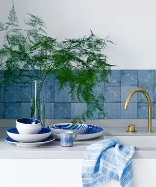 כיצד להתקין דוגמה של backsplash, עם אריחים כחולים ודיס כהה במטבח לבן.