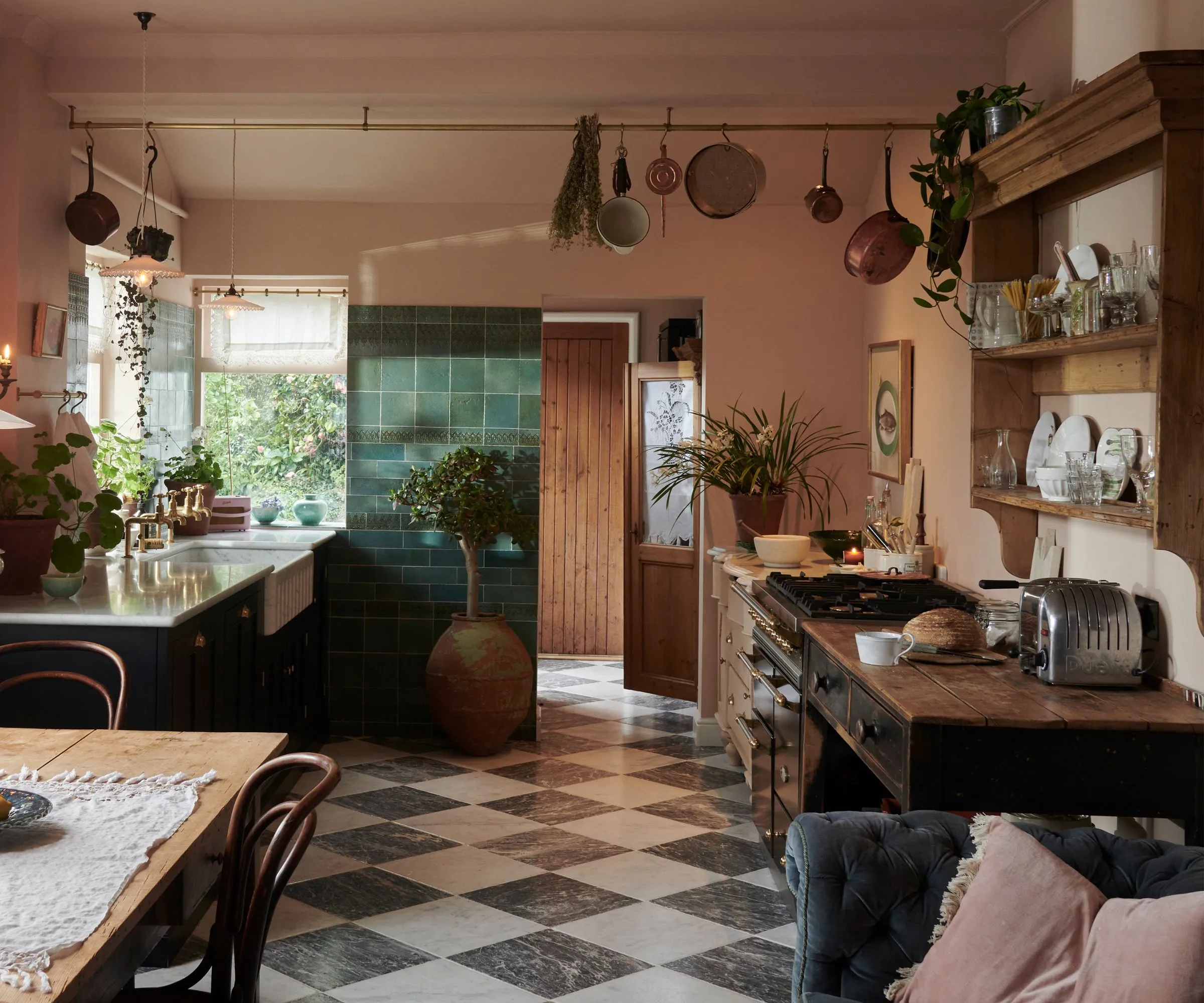 Útulná zelená a ružová kuchyňa zdobená na zimu kužeľovými sviečkami vrstvenými textíliami a otvorenými policami na vystavenie peknej keramiky' loading='lazy' title=