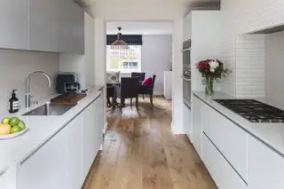 Cozinha com armários brancos contemporâneos e piso de madeira