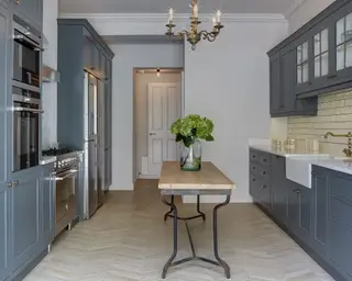 Uma cozinha moderna com móveis azuis, prateleiras de madeira aconchegantes e uma ilha com tampo de pedra