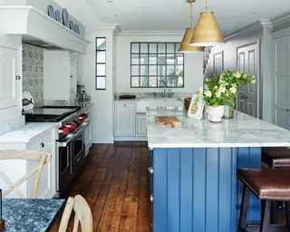 Uma cozinha com azulejos backsplash brancos de parede a parede e armários azuis