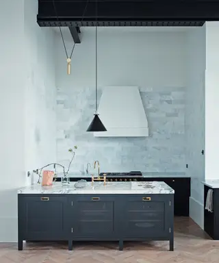 Uma única cozinha com armários azuis e mosaicos em frente a uma parede rosa