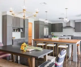 Cocina gris con doble isla y mesa de comedor.