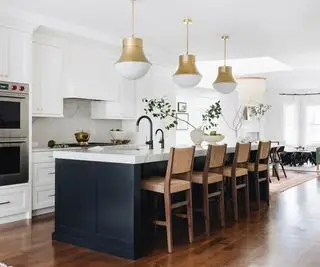 Cocina blanca con isla negra y sillas de madera.