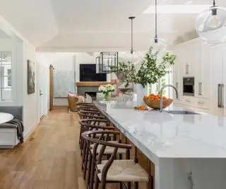 Cocina blanca con gran isla de cocina con encimera de mármol.