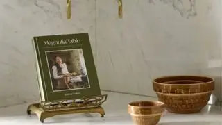 O livro de receitas Magnolia em um suporte com suas tigelas do lado direito