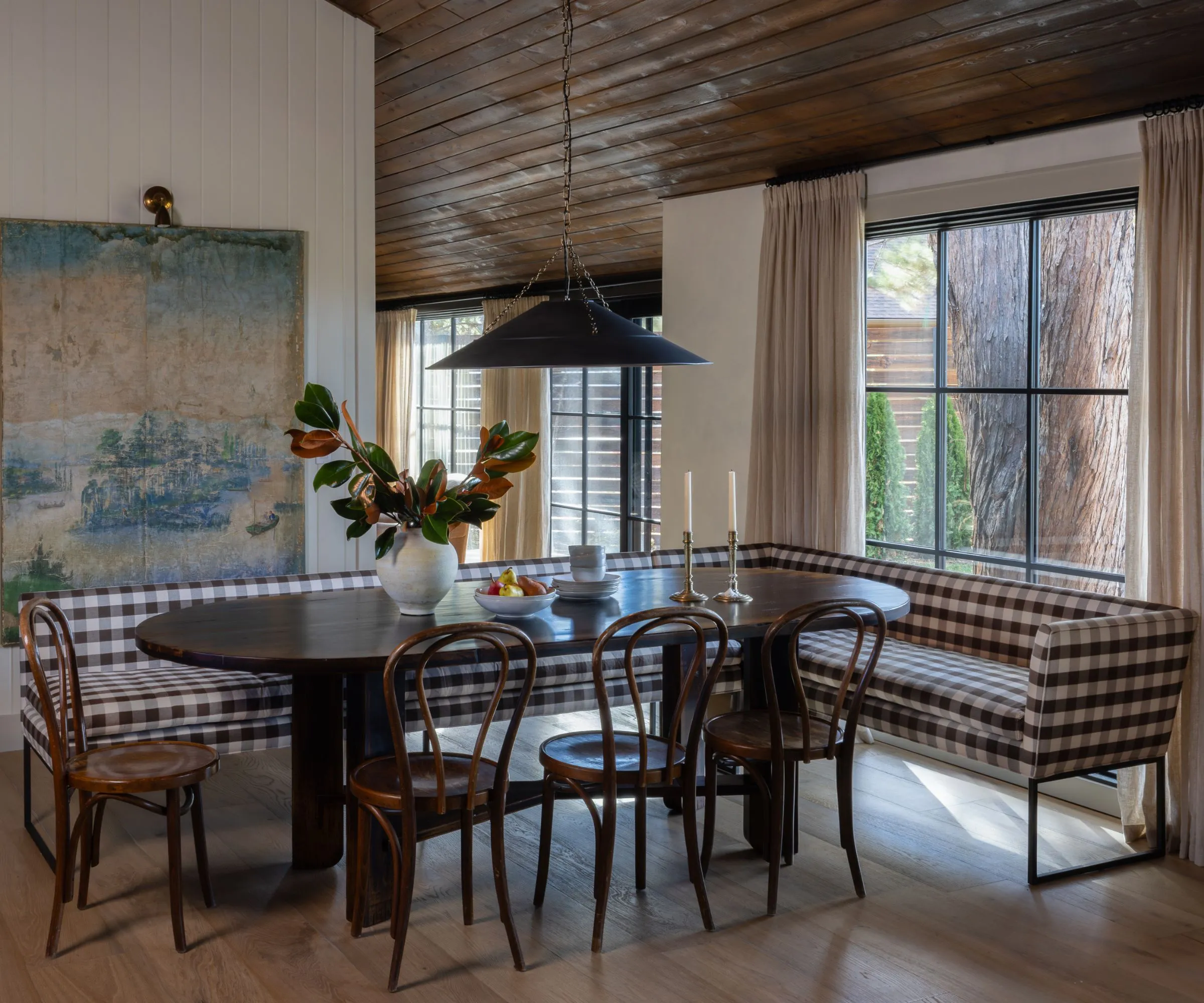 Ein Blick in die Küche, eingerahmt von Holztüren mit Blick auf die Marmorinsel und einem großen Bogenfenster mit Blick auf grüne Bäume. Zwei weiße Pendelleuchten hängen symmetrisch über der Insel' loading='lazy' title=