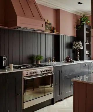 mørkegrått kjøkken med rosa vegger og kjøkkenhette